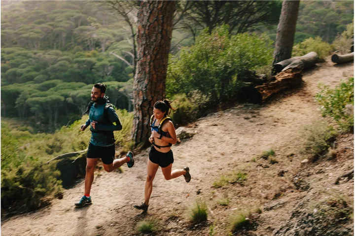 Two people running together on a forest trail.